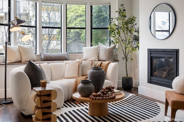 living area with a glass covered fireplace, wood finished floors, and baseboards