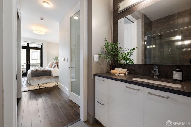 full bath featuring french doors, wood-type flooring, a stall shower, vanity, and ensuite bath