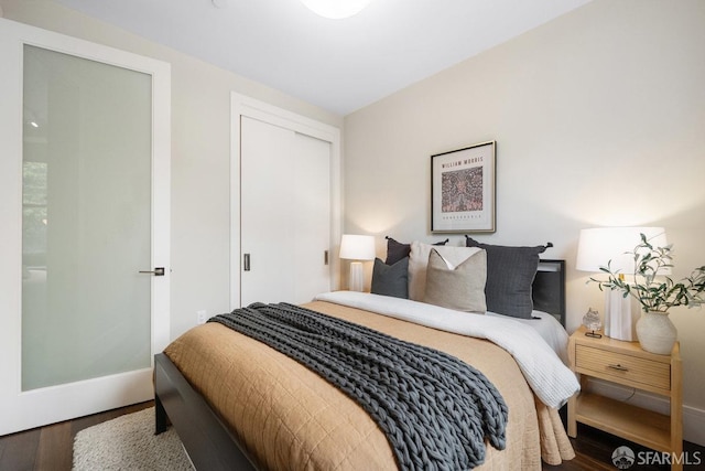 bedroom with a closet, wood finished floors, and baseboards