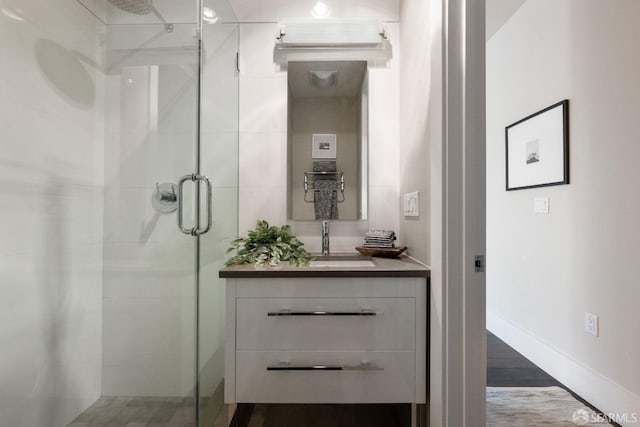 full bathroom featuring a stall shower, vanity, baseboards, and wood finished floors