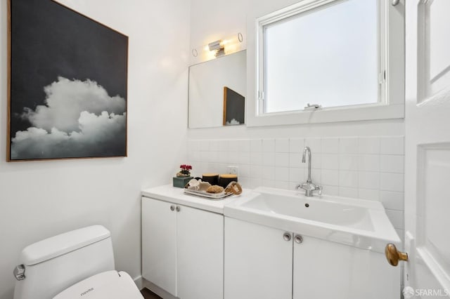 bathroom with vanity, toilet, and tasteful backsplash