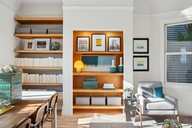 living area with built in features, light wood-type flooring, and ornamental molding