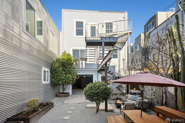 rear view of property with a fire pit and a patio