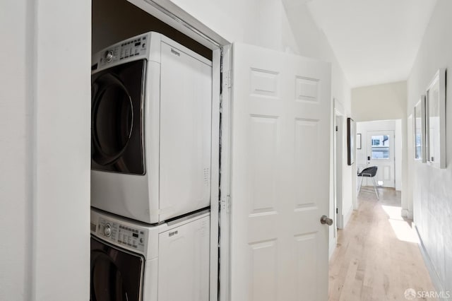 clothes washing area with light hardwood / wood-style floors and stacked washer / dryer