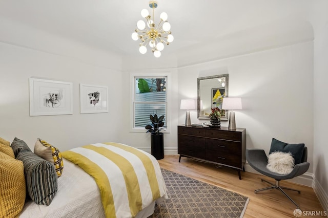 bedroom with light hardwood / wood-style flooring and an inviting chandelier