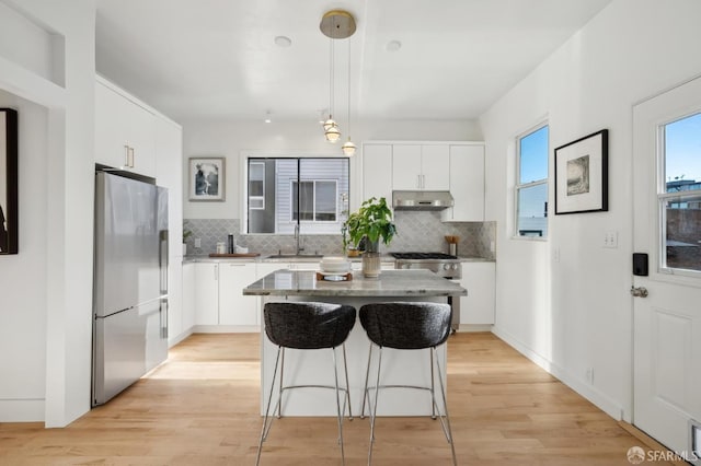 kitchen with stainless steel fridge, white cabinetry, a kitchen island, and pendant lighting