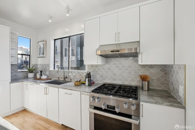 kitchen with exhaust hood, sink, light stone countertops, gas stove, and white cabinetry