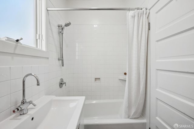 bathroom featuring backsplash, tile walls, sink, and shower / tub combo with curtain