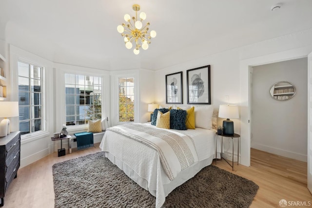 bedroom with light hardwood / wood-style flooring and an inviting chandelier