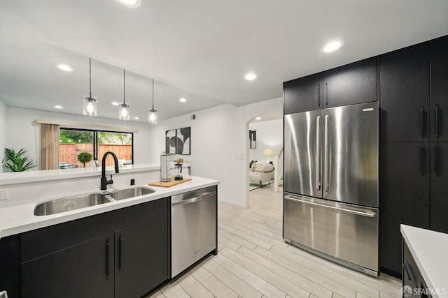 kitchen with a sink, dark cabinets, stainless steel appliances, and light countertops