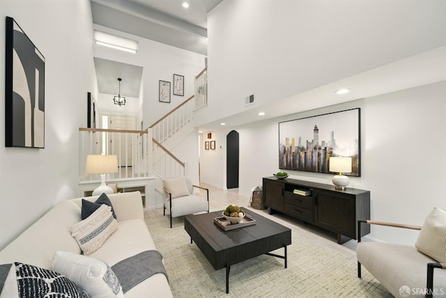 living area featuring recessed lighting, arched walkways, stairs, and visible vents