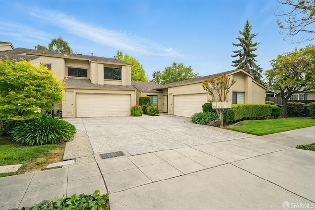 view of front of home with an attached garage, stucco siding, and concrete driveway