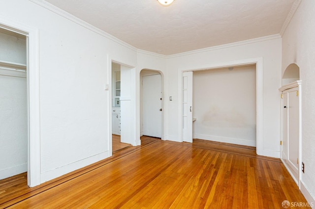 unfurnished bedroom featuring wood-type flooring, a closet, and crown molding