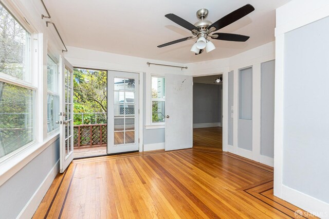 spare room with plenty of natural light, ceiling fan, and hardwood / wood-style flooring