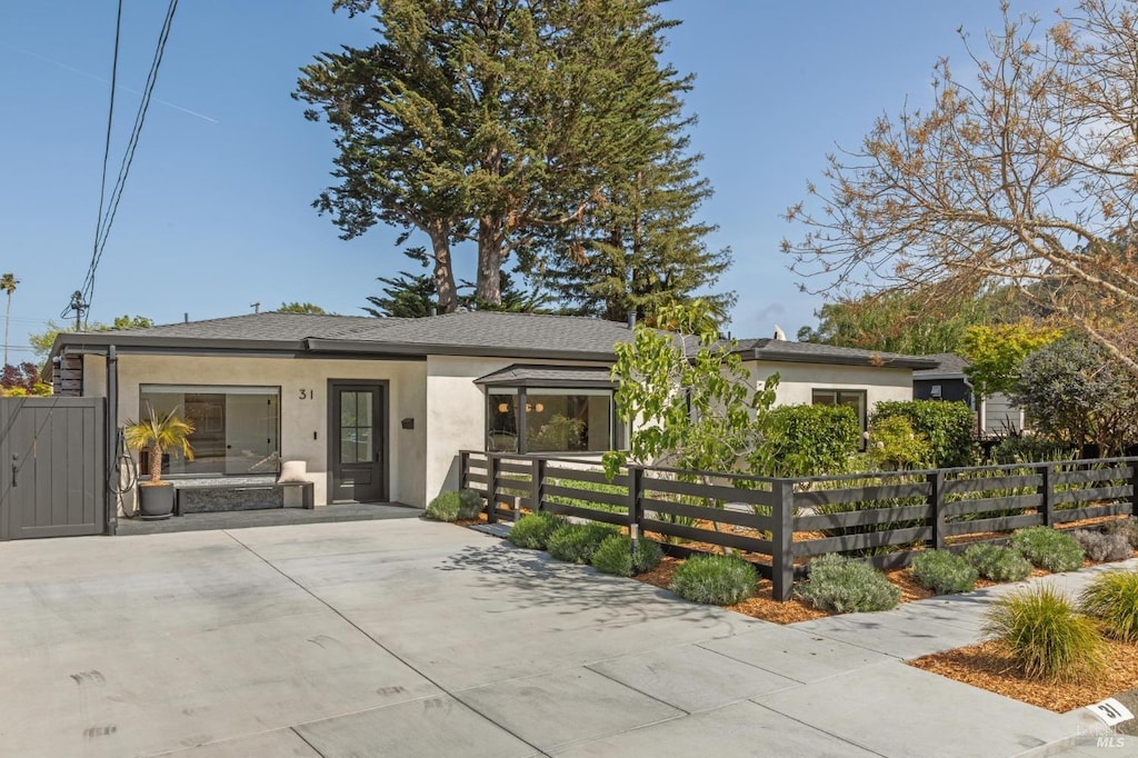 ranch-style house featuring a fenced front yard and stucco siding