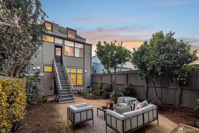 back of property at dusk featuring a patio, fence, stairway, and an outdoor hangout area