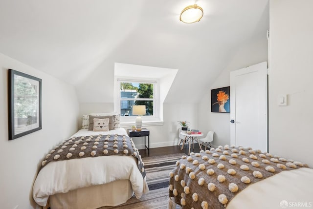 bedroom featuring lofted ceiling, wood finished floors, and baseboards