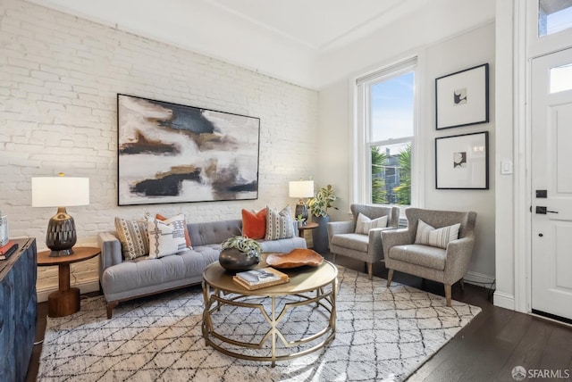 living room with brick wall, wood finished floors, and baseboards