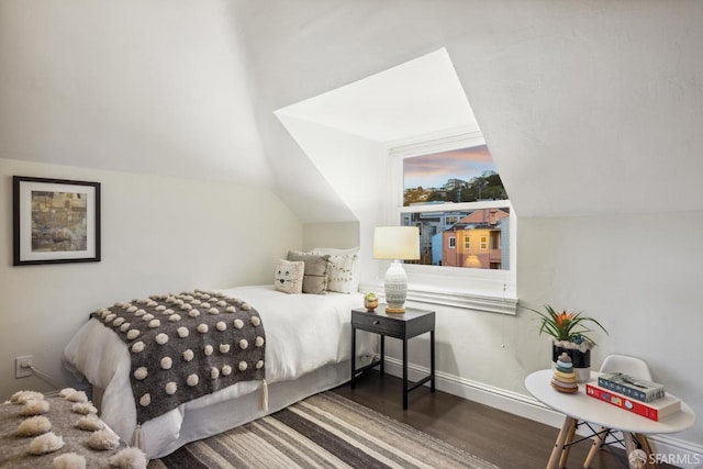 bedroom featuring lofted ceiling, wood finished floors, and baseboards