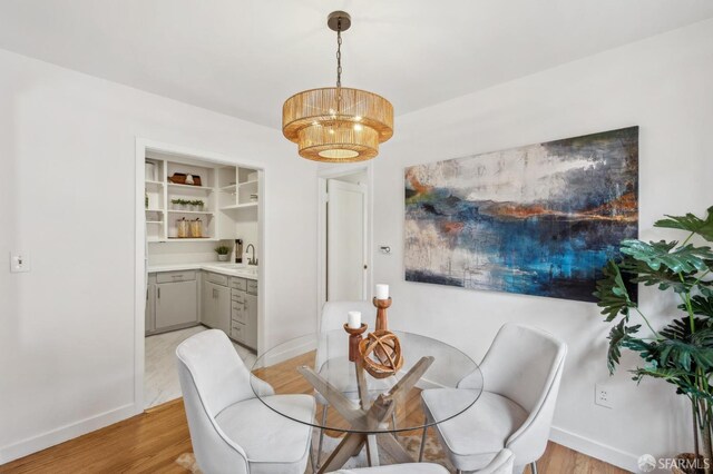 dining area featuring baseboards, a chandelier, and light wood finished floors