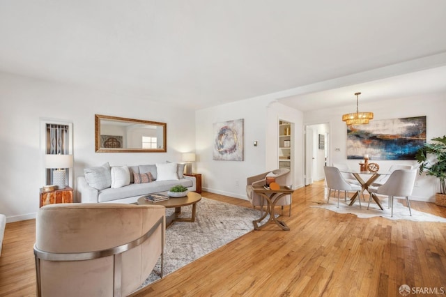 living area with light wood-style floors, baseboards, and an inviting chandelier