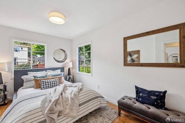 bedroom featuring wood finished floors, baseboards, and multiple windows