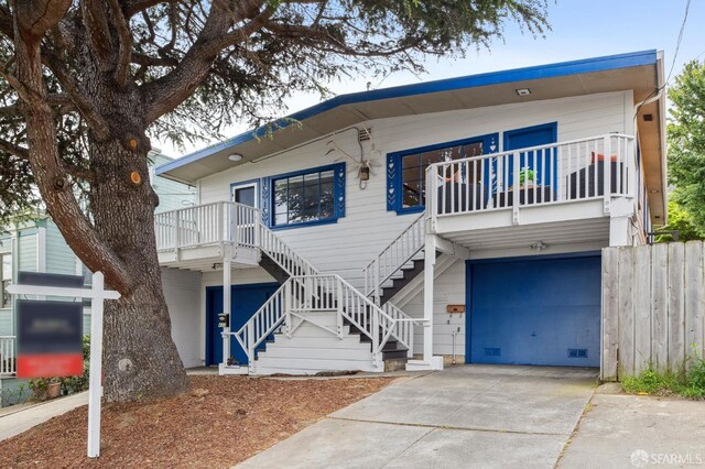 view of front facade featuring concrete driveway, fence, stairs, and a garage