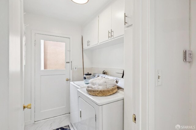 laundry room featuring cabinet space, marble finish floor, and separate washer and dryer