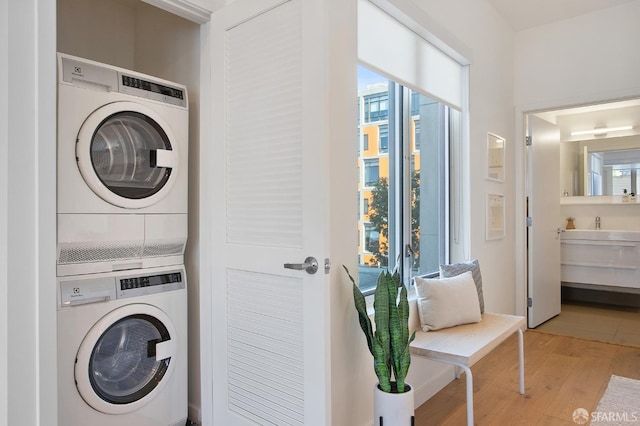 laundry area featuring stacked washer / drying machine and light wood-type flooring