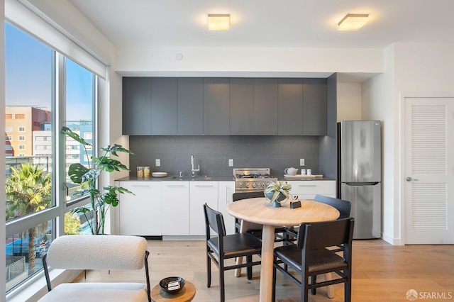 kitchen featuring decorative backsplash, white cabinetry, stainless steel refrigerator, and light hardwood / wood-style flooring