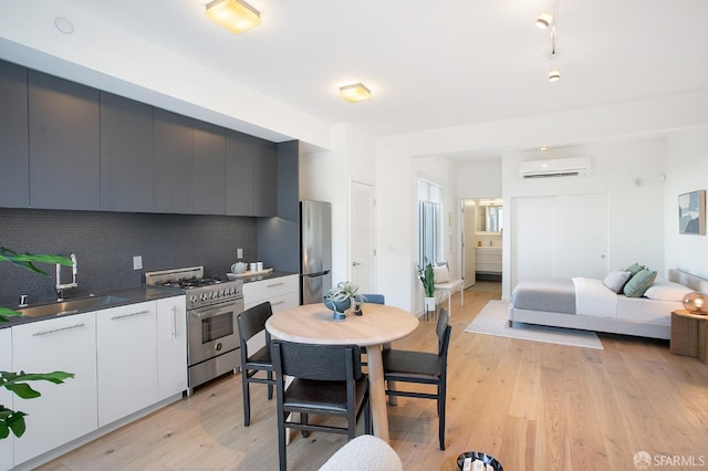 kitchen with appliances with stainless steel finishes, backsplash, a wall unit AC, sink, and white cabinets