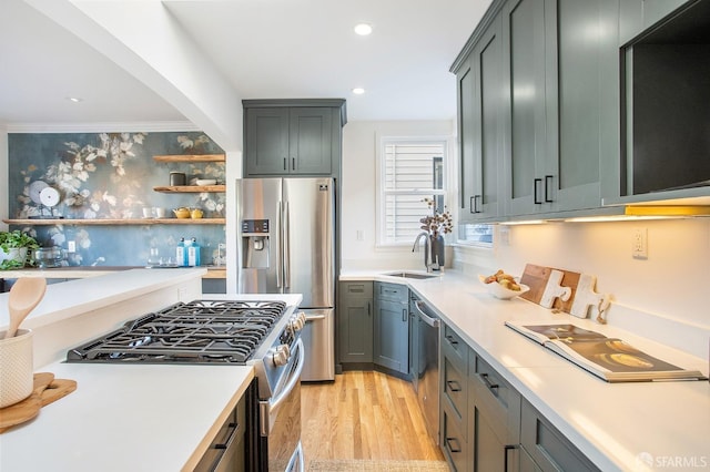 kitchen with appliances with stainless steel finishes, light wood-type flooring, ornamental molding, and sink