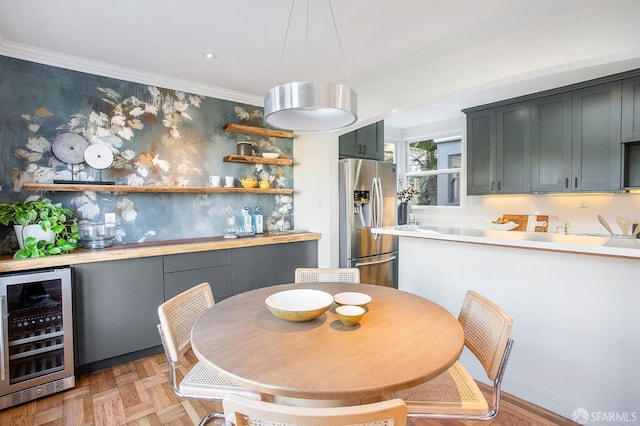 dining space featuring beverage cooler, crown molding, and light parquet flooring