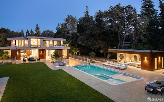 back of property featuring outdoor lounge area, a balcony, a patio area, a yard, and a pool with connected hot tub