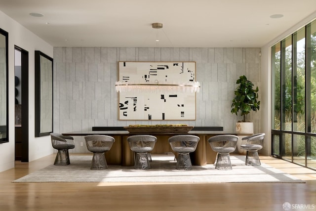 sitting room with a wall of windows, wood walls, and light hardwood / wood-style flooring