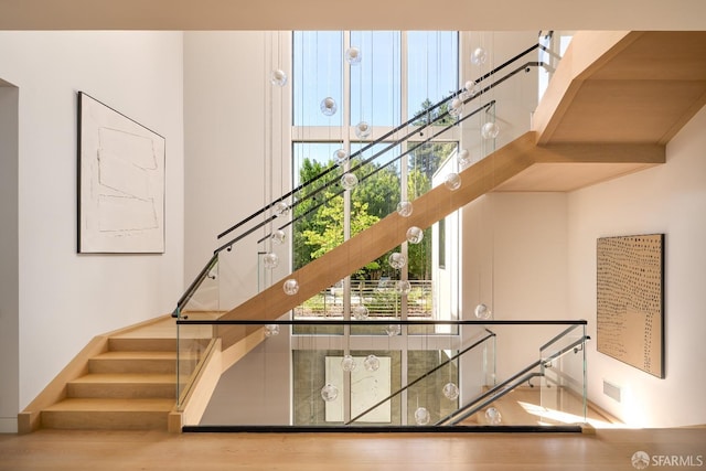 staircase with a high ceiling, wood finished floors, and baseboards