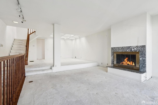 interior space with light colored carpet, a premium fireplace, and rail lighting