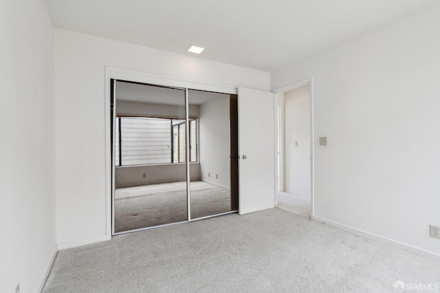 unfurnished bedroom with a closet and light carpet