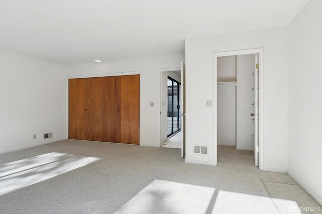 unfurnished bedroom featuring a walk in closet and light colored carpet