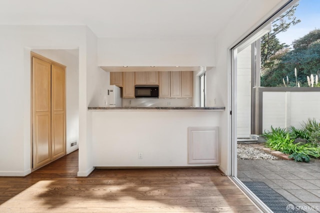 kitchen with hardwood / wood-style flooring, light brown cabinetry, and white fridge