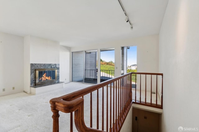 stairs featuring a fireplace, carpet floors, and rail lighting