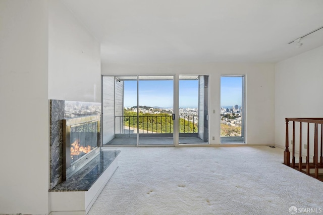 unfurnished living room featuring light carpet, rail lighting, and a premium fireplace