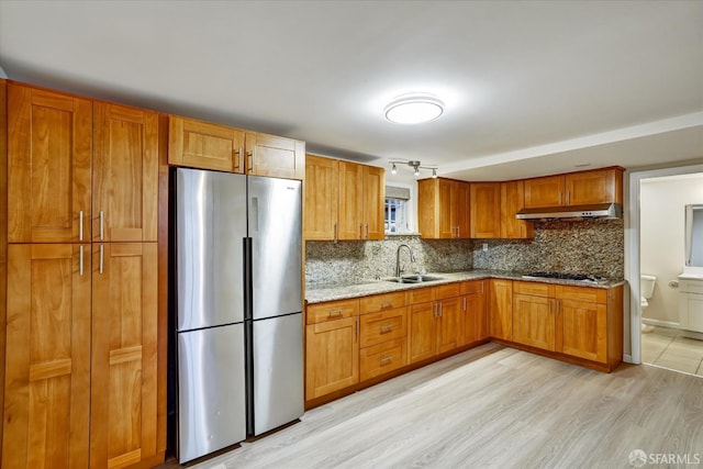 2486 26th Ave, Oakland, CA 94601 - kitchen featuring freestanding refrigerator, under cabinet range hood, stovetop, tasteful backsplash, and light stone counters