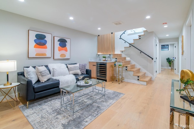 living room with bar, wine cooler, and light hardwood / wood-style floors