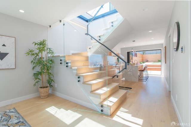 stairway with wood-type flooring and a skylight