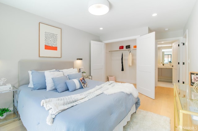 bedroom featuring connected bathroom, light hardwood / wood-style flooring, and a closet