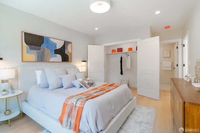 bedroom with light hardwood / wood-style floors and a closet