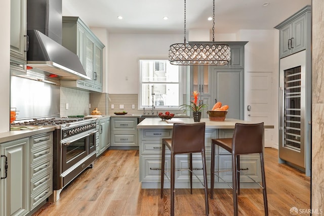850 Powell St Unit 104, San Francisco, CA 94108 - kitchen featuring wall chimney range hood, range with two ovens, beverage cooler, gray cabinets, and light countertops