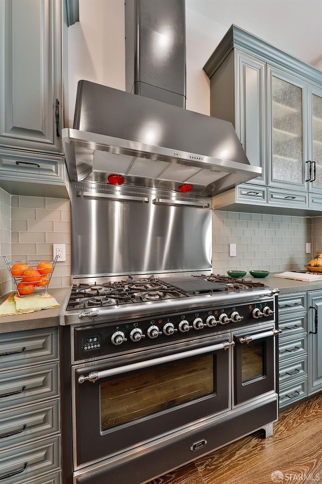 850 Powell St Unit 104, San Francisco, CA 94108 - kitchen with wall chimney range hood, range with two ovens, tasteful backsplash, and light countertops