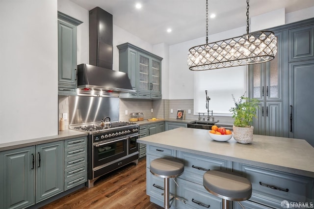 850 Powell St Unit 104, San Francisco, CA 94108 - kitchen with wall chimney range hood, range with two ovens, dark wood-type flooring, a kitchen bar, and tasteful backsplash